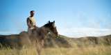 Man on horseback riding through the grass