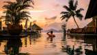 Person relaxing in the pool as the sunsets over the Seychelles islands